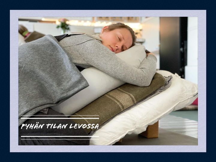 Nainen makaa vatsallaan peite päällään ja iso tyyny allaan.
