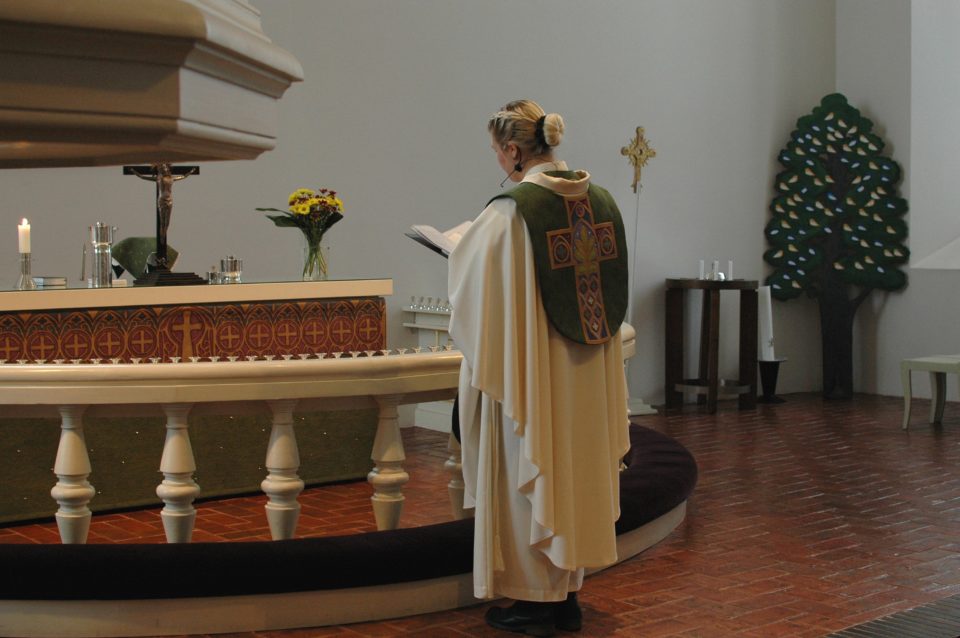 Pastori Jaana Kivekäs seisoo kääntyneenä Marian kirkon alttariin päin