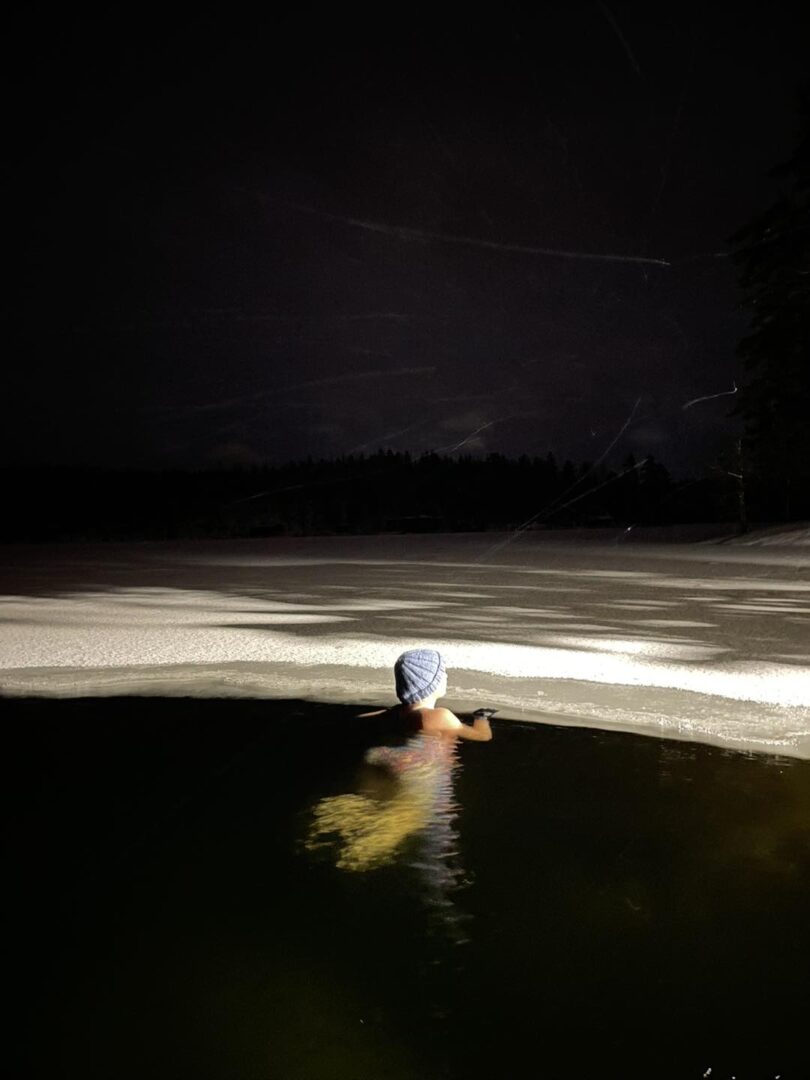 Nainen ui pipo päässä avannossa.