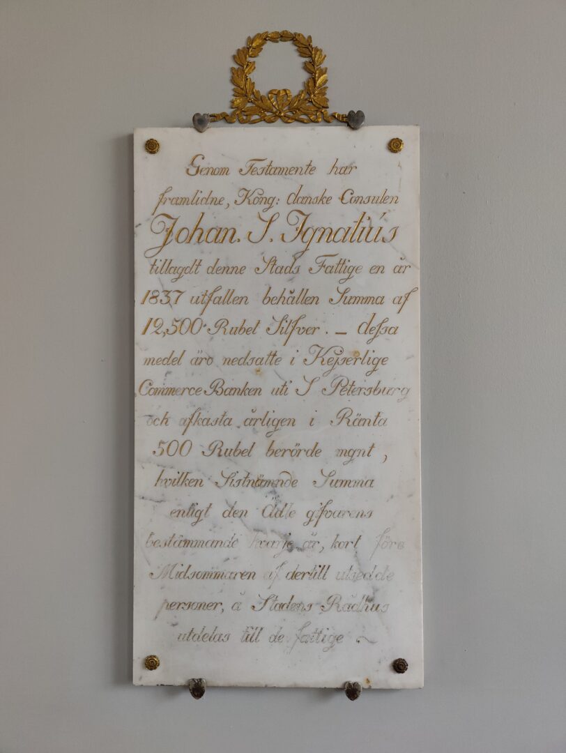 Ingnatius testamentista kertova laatta Johanneksen kirkon seinässä.