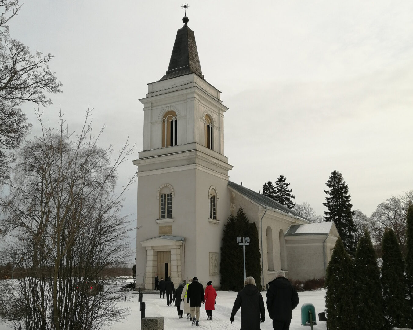 Talvinen Marian kirkko. Ihmisiä kulkemassa kirkkoon.