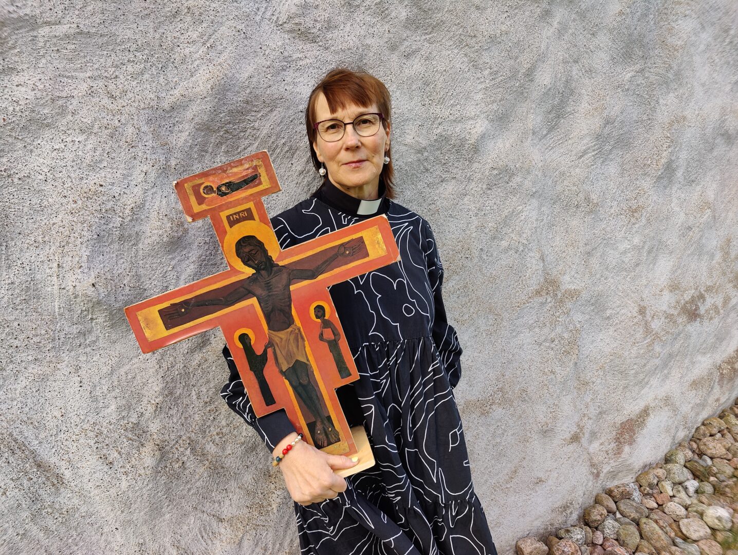 Pastori Anita Venäläinen pitää ristiä.