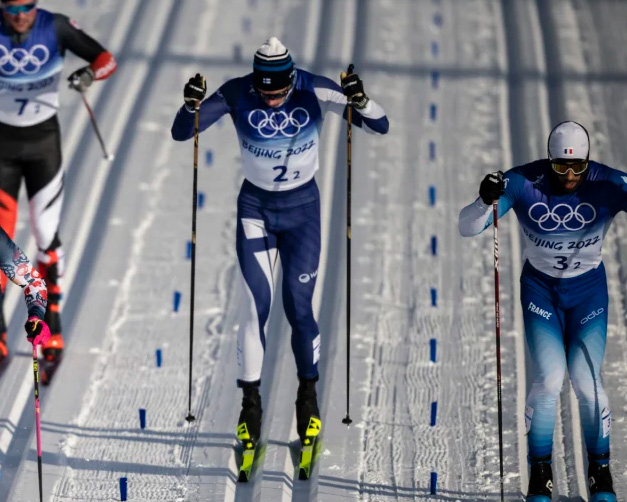 Hiihtäjiä kilpaladulla sinivalkoisissa asuissa.