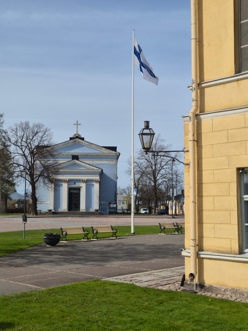 Johanneksen kirkko. Etualalla raatihuoneen kulmaa. Suomen lippu liehuu lipputangossa.