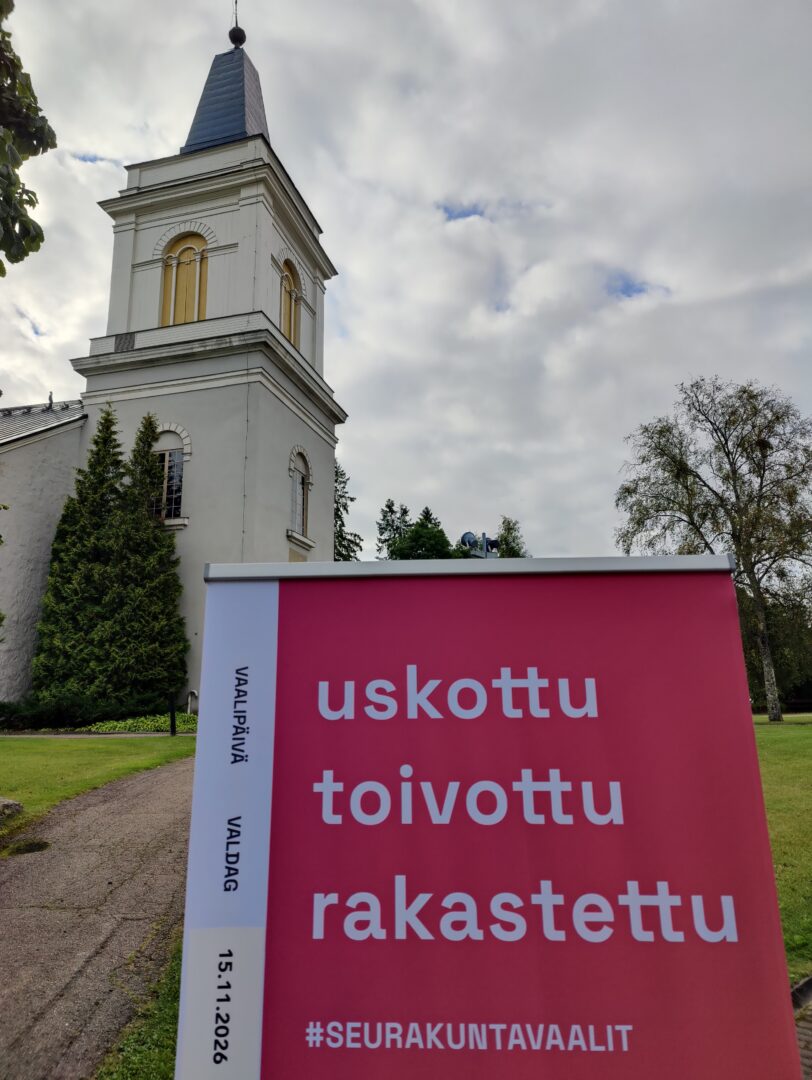 Marian kirkon edustalla seurakuntavaalien roll up tekstillä uskottu, toivottu, rakastettu.