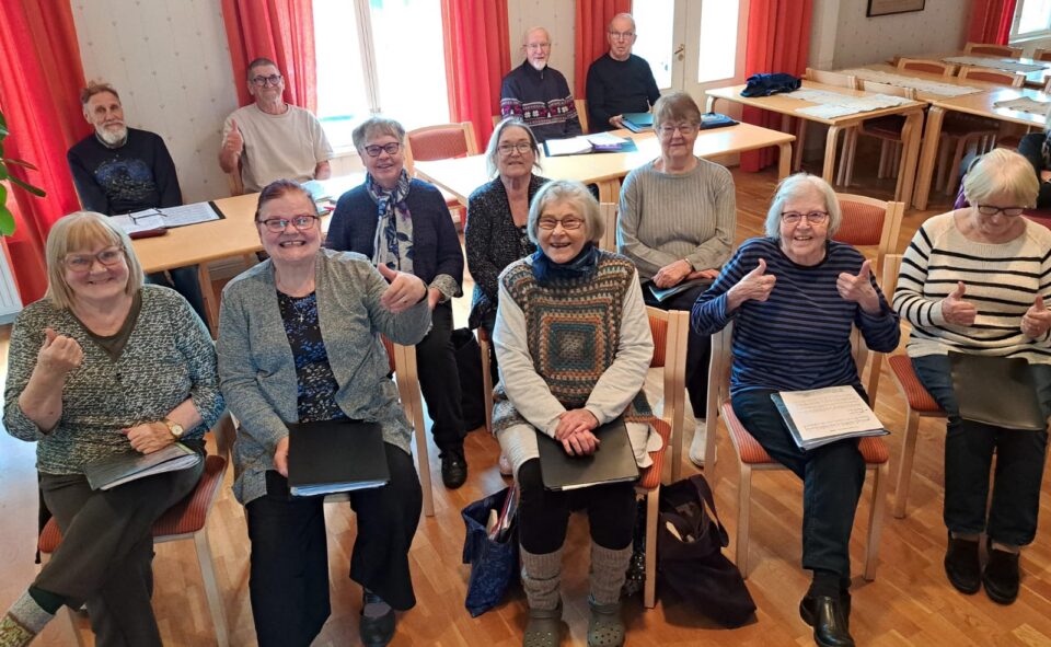 Miehikkälän kirkkokuoro istuu Miehikkälän seurakuntakodin tuoleilla harjoittelemassa.
